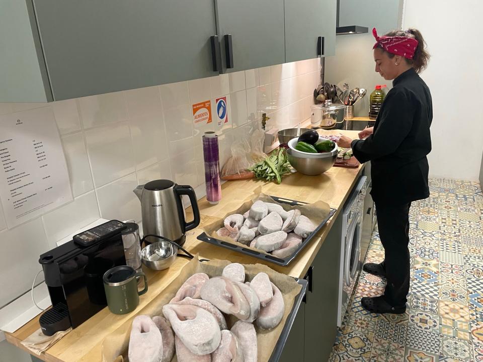 A chef preparing a meal in a kitchen with a mosaic tile floor.