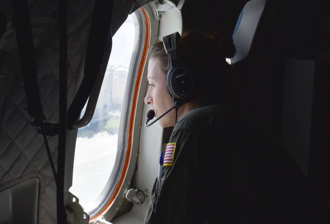 A Coast Guard flight crew member looks out the window as she’s positioned to watch for any danger on a flight to Southwest Florida on Sunday, Oct. 2, 2022.