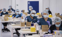 FILE - In the May 10, 2021, file photo, technicians prepare Pfizer vaccines at the newly opened COVID-19 Vaccination Centre in Sydney, Australia. Some wealthy nations that were most praised last year for controlling the coronavirus are now lagging far behind in getting their people vaccinated — and some, especially in Asia, are seeing COVID-19 cases grow. (James Gourley/Pool Photo via AP, File)