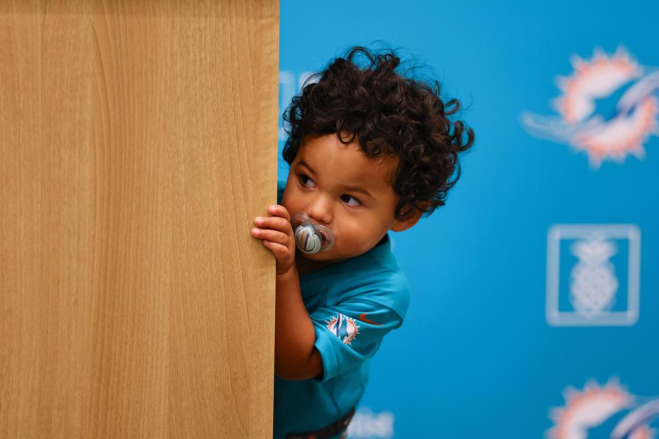 Jul 28, 2024; Miami Gardens, FL, USA; Ace, the son of Miami Dolphins quarterback Tua Tagovailoa (not pictured), looks on from behind the podium as his fathers talks to reporters during a press conference at Baptist Health Training Complex. Mandatory Credit: Sam Navarro-USA TODAY Sports