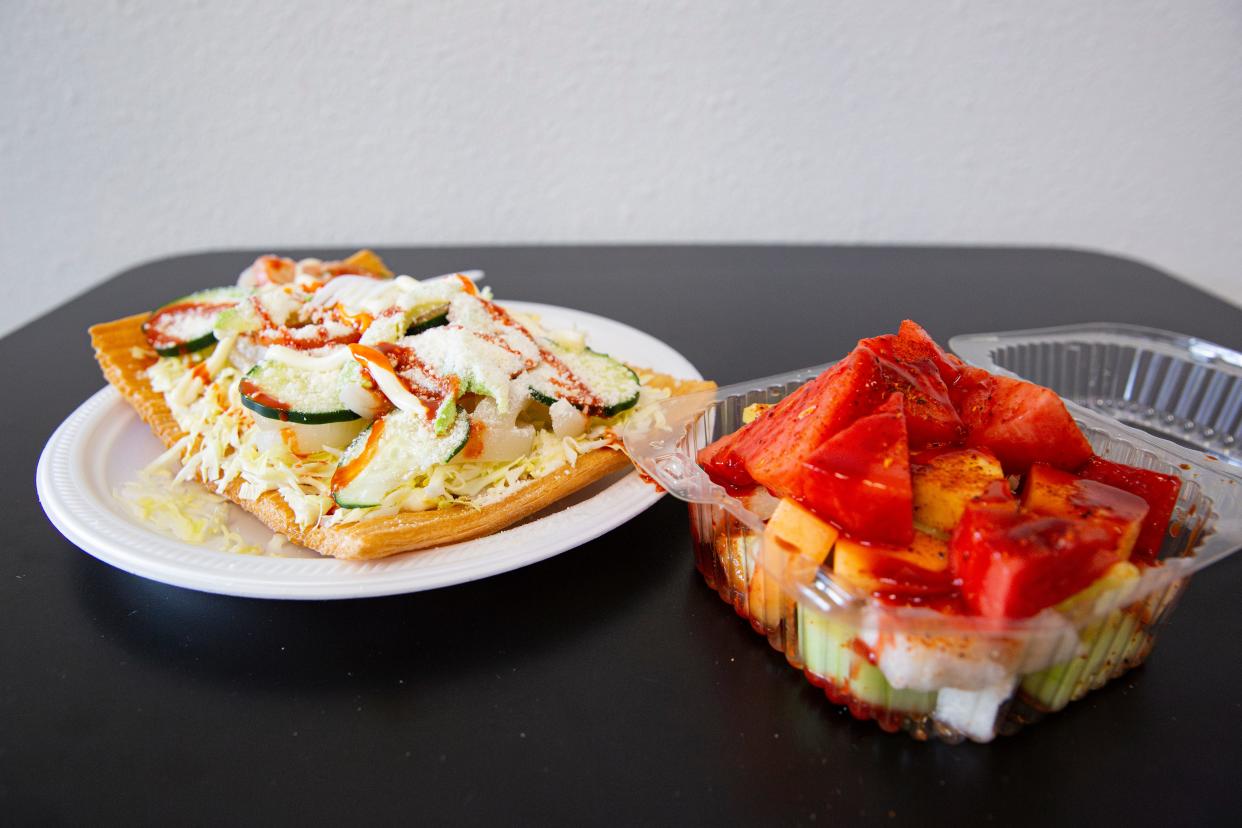 A $10 chicharron preparado, left consists of chicharron, mayonnaise, cabbage, pork rinds, cucumber, tomato, avocado, Valentina sauce and cotija cheese. An $8 fruit cocktail consists of a choice of fruits with Tajin, chamoy and Valentina sauce.