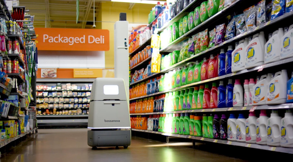 A small robot navigating down a store aisle while scanning items on the shelves.
