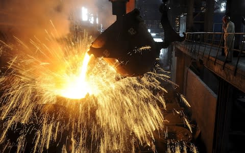 An employee monitors molten iron being poured into a container  - Credit: Reuters/Jianan Yu 