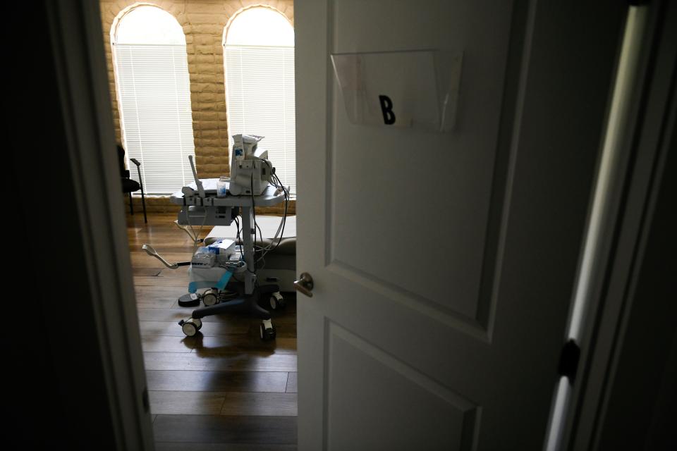 A door stands ajar and a patient room at a clinic.