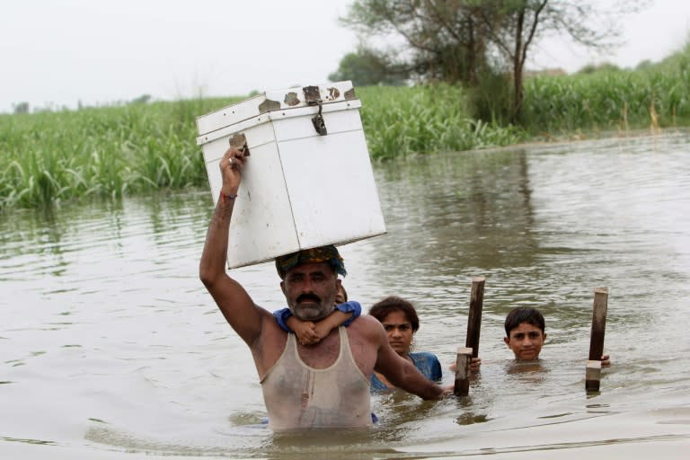 Pakistani villagers wade through floodwaters in the Layyah district of Punjab province on July 23, 2015