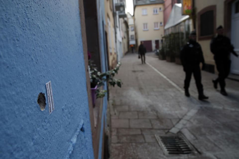 Policías franceses patrullan las calles de Estrasburgo, en el oriente de Francia, y pasan por una pared con un hoyo de bala tras un ataque armado que dejó tres muertos y 13 heridos, el jueves 13 de diciembre del 2018. (AP Foto/Christophe Ena)