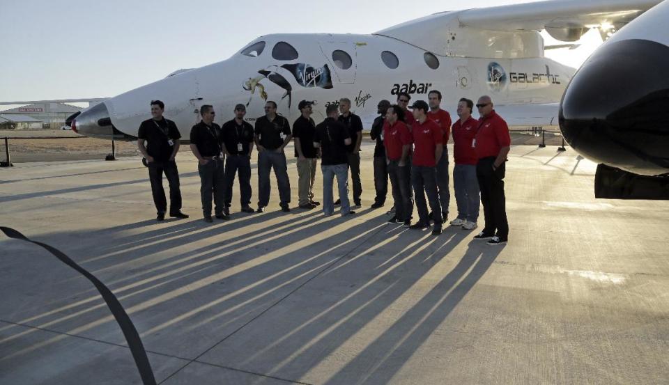 FILE- In this Wednesday, Sept. 25, 2013 file photo SpaceShipTwo is seen mounted under its mother ship White Knight with its support crew at a Virgin Galactic hangar at Mojave Air and Space Port in Mojave, California. One lucky citizen of the oil-rich United Arab Emirates could soon get the chance to be rocketed into space. Government-backed Aabar Investments on Sunday, April 20, 2014, announced the start of a competition to award an Emirati a free spot aboard Virgin Galactic's spaceship when it begins ferrying space tourists briefly into space. (AP Photo/Reed Saxon, File)