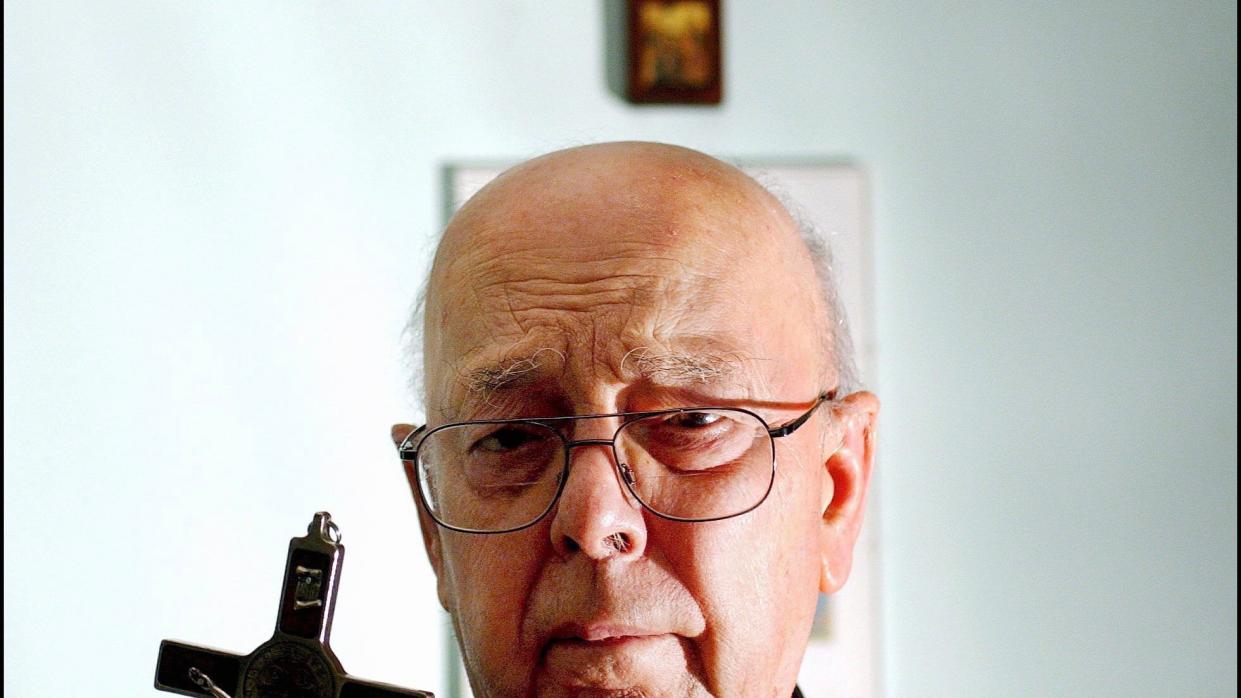 father gabriele amorth holding a crucifix in front of religious articles on a wall