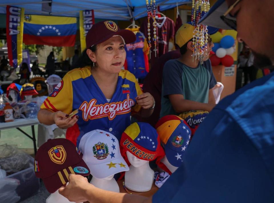 Sandra Quintero, left, helps a customer as he inquired about Venezuelan themed items at Quintero’s booth. Members of the Venezuelan exile community gathered in the shade at the local eatery Arepazo in Doral, Florida, on Sunday, July 28, 2024, in Miami, Florida, to monitor the election in their homeland.