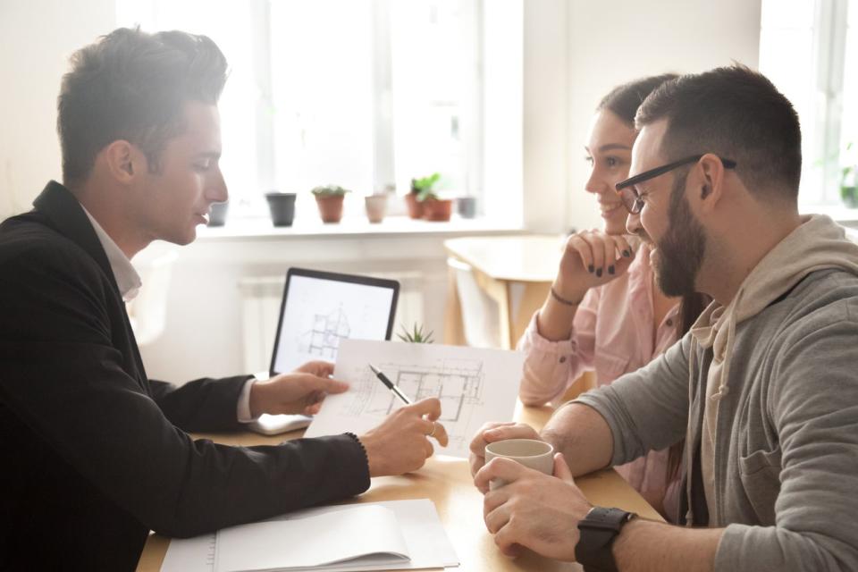 Three people discuss a home renovation plan.