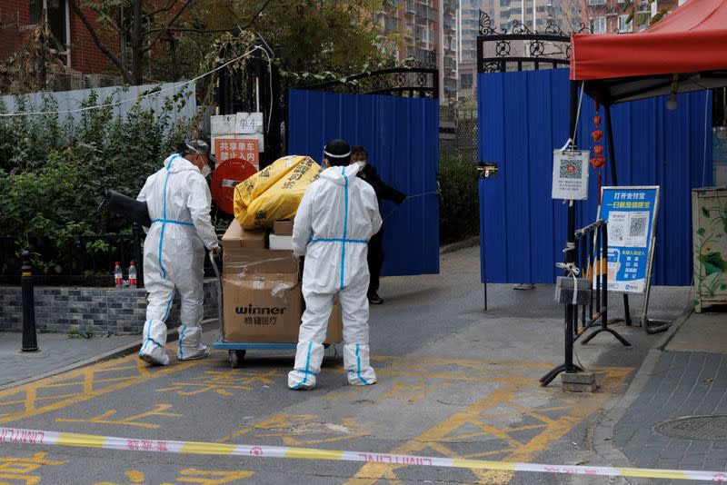 Men wearing protective suits deliver parcels to a residential compound that was placed under lockdown as outbreaks of coronavirus disease (COVID-19) continue in Beijing