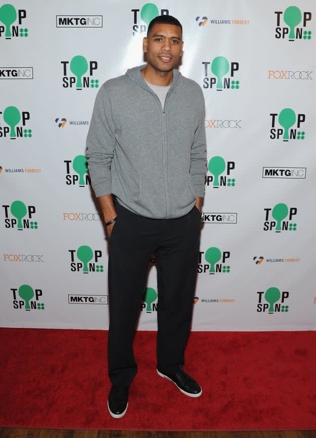 Allan in a gray hoodie and black pants smiling on the red carpet