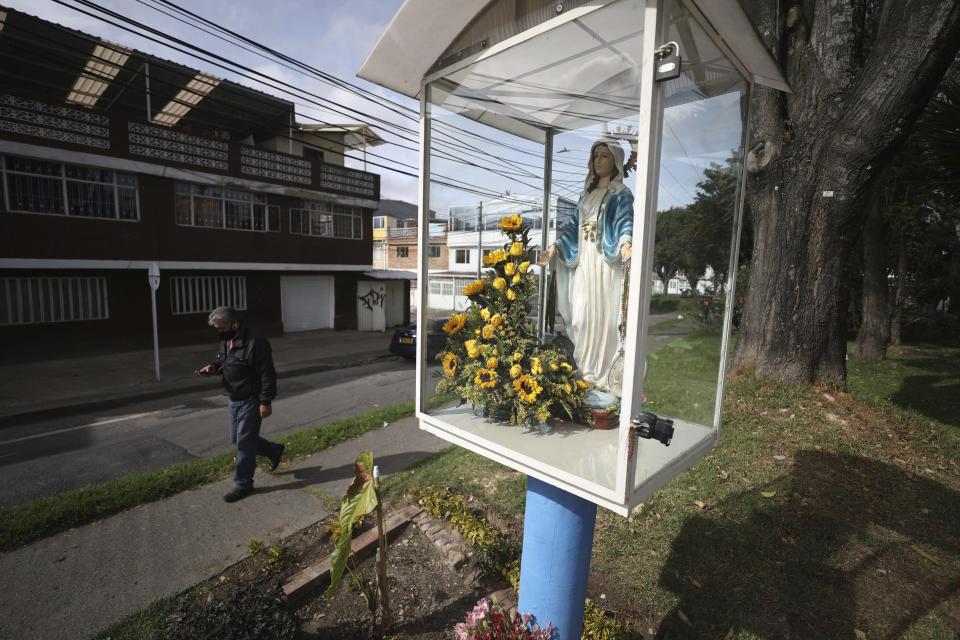 Foto del 5 de agosto del 2020 de una estatua de la Virgen María en un parque de Bogotá. Solo una persona se ve en la calle como consecuencia de la cuarentena asociada con el coronavirus, que ya lleva cuatro meses. (AP Photo/Fernando Vergara)