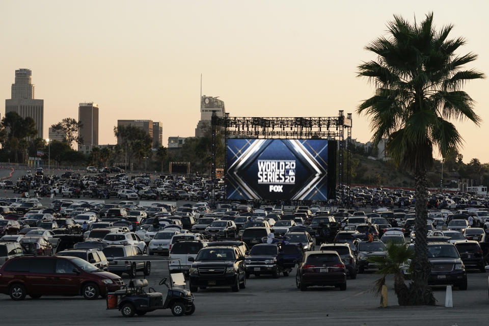 Los aficionados de los Dodgers miran desde sus autos el sexto juego de la Serie Mundial contra Tampa Bay en que su equipo se coronó campeón en el estacionamiento de su estadio en Los Ángeles. El estadio se convirtio en un drive-in, el viejo sistema en el que la gente veía películas desde sus autos y que trajo alivio a muchos en medio de la pandemia. (AP Photo/Ashley Landis, File)