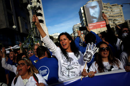 Nurses hold white carnations and hand-shaped placards reading "enough" during a protest march in Lisbon, Portugal, March 8, 2019. REUTERS/Pedro Nunes