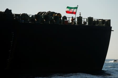 A crew member raises the Iranian flag at Iranian oil tanker Adrian Darya 1, before being named as Grace 1, as it sits anchored after the Supreme Court of the British territory lifted its detention order, in the Strait of Gibraltar