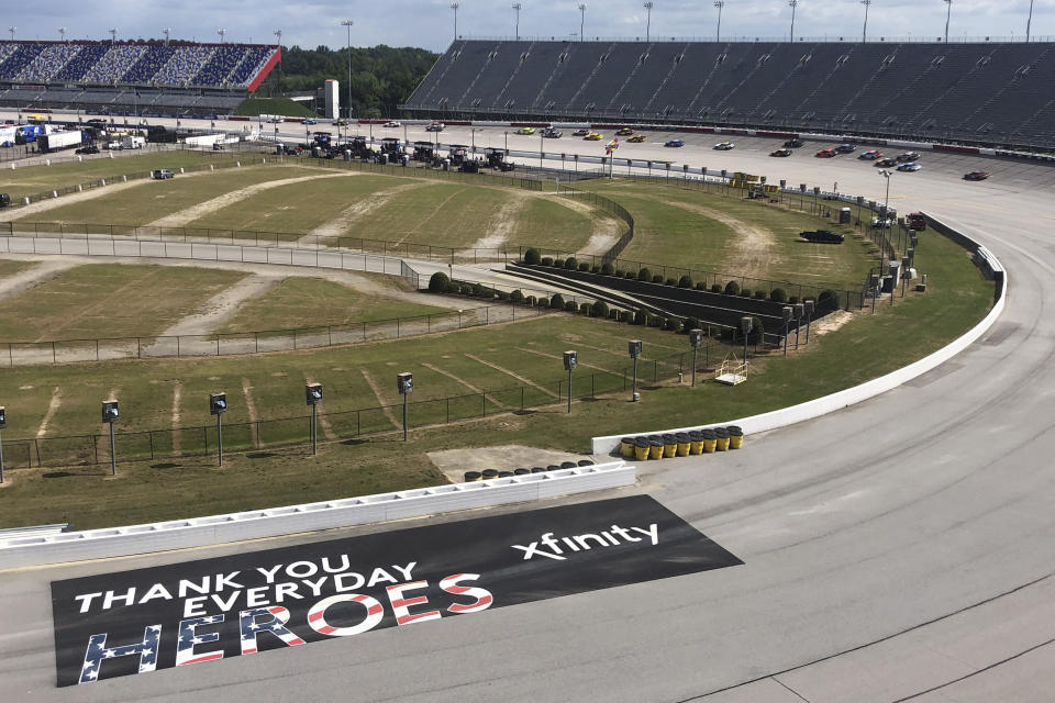 Cars go through a turn past a sign thanking people working during the coronavirus pandemic at Darlington Raceway Sunday, May 17, 2020, in Darlington, S.C. NASCAR, which has been idle for 10 weeks because of the pandemic, made its return with the Real Heroes 400 Nascar Cup Series auto race. (AP Photo/Jenna Fryer)