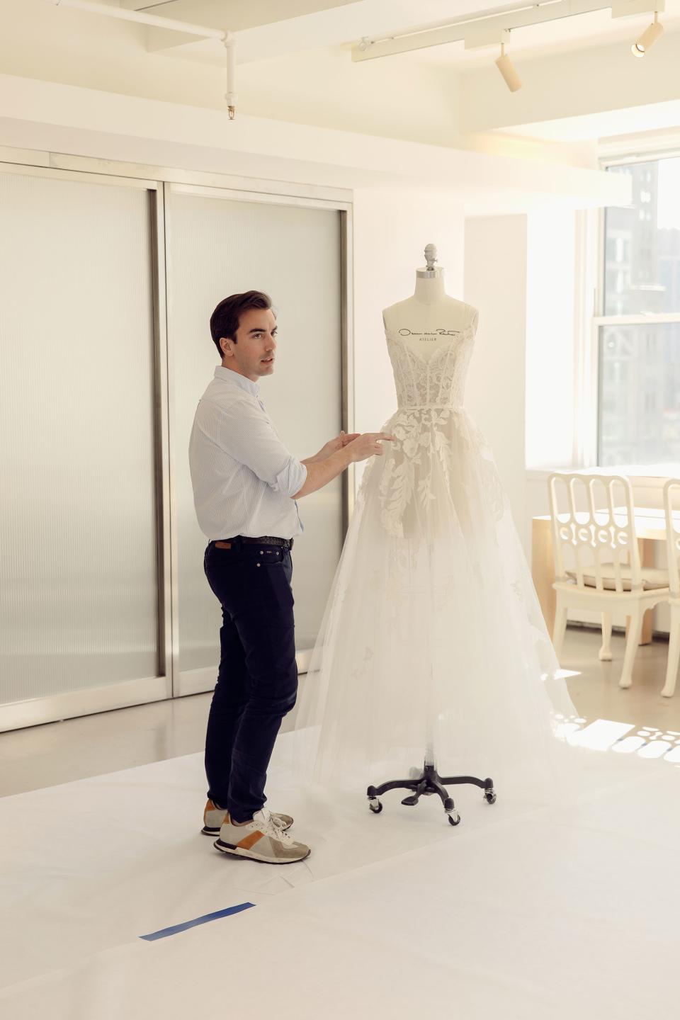 Oscar de la Renta’s Fernando Garcia explains how additional Lyon lace will be added to the bodice of the dress during one of Caroline’s dress fittings in New York.