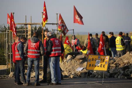 Striking French labour union employees stand near a barricade to block the entrance of the depot of the SFDM company near the oil refinery to protest the labour reforms law propal, in Donges, France, May 26, 2016. REUTERS/Stephane Mahe