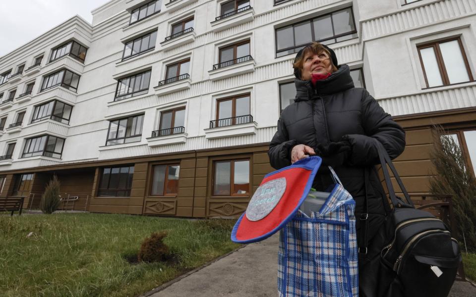 A woman stands outside an apartment block - SERGEI ILNITSKY/EPA-EFE/Shutterstock