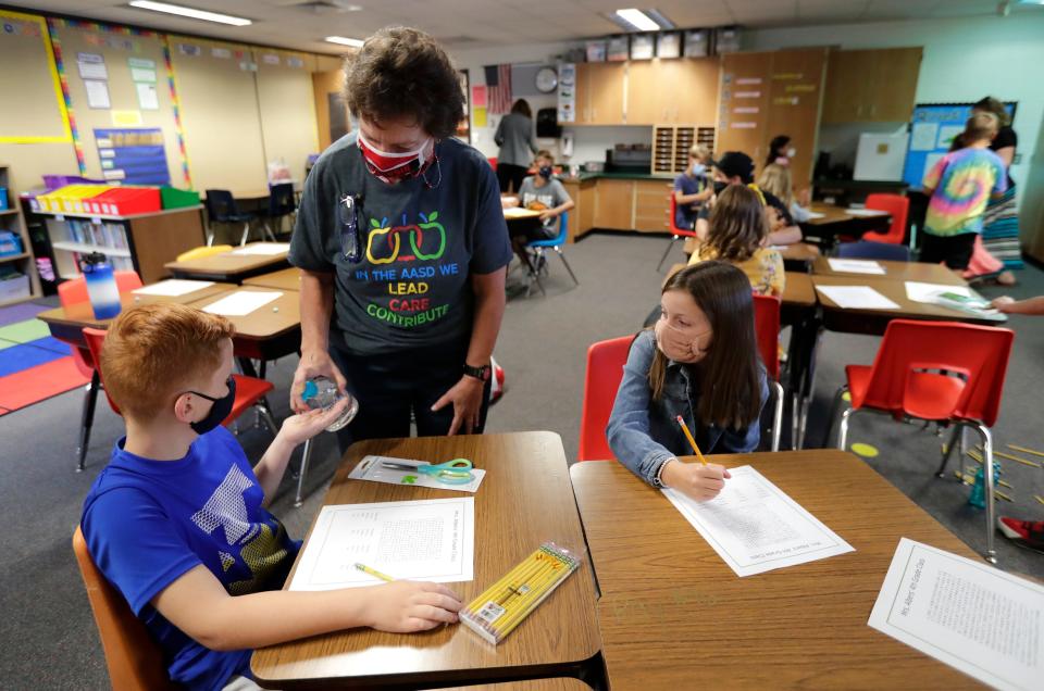 Fourth-grade teacher Jane Anderson-Wood gives hand sanitizer to Keenan Nelson, left, and Zoe Korth during the first day of school at Horizons Elementary School in Appleton.