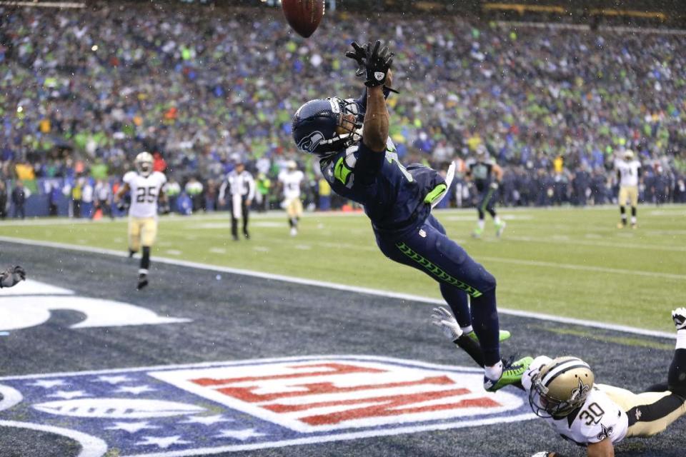 Seattle Seahawks wide receiver Percy Harvin, top, jumps for a pass, which he did not catch, over New Orleans Saints defensive back Trevin Wade during the second quarter of an NFC divisional playoff NFL football game in Seattle, Saturday, Jan. 11, 2014. Harvin was injured on the play. (AP Photo/Ted S. Warren)