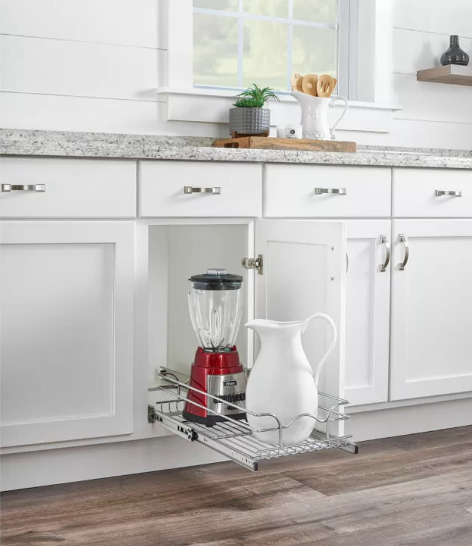 a metal wire basket rolling out of a white cabinet