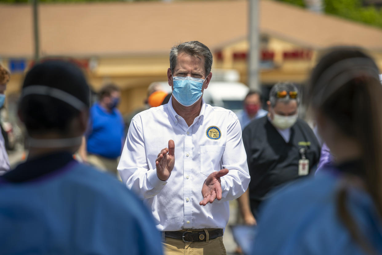 Georgia Governor Brian Kemp applauds healthcare workers for their service while touring a community COVID-19 testing site in the parking lot of La Flor de Jalisco #2 during a visit to Gainesville on May 15, 2020.  (Alyssa Pointer/Atlanta Journal-Constitution via AP)