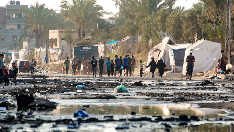 Displaced Palestinians walk on a street covered with stagnant wastewater in Deir el-Balah, central Gaza, on July 19. A ceasefire would allow a moment of relief for Gazans, after nearly a year of Israeli attacks. - Bashar Taleb/AFP/Getty Images