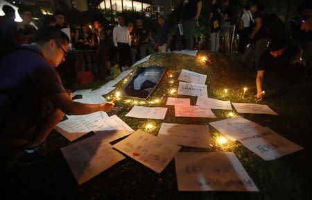 People light candles next to signs at a candlelight vigil in solidarity with protesters of the "Occupy Central" movement in Hong Kong, at Hong Lim Park Speakers' Corner in Singapore October 1, 2014. REUTERS/Edgar Su