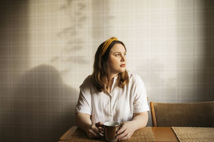 a woman drinking coffee looking out the window