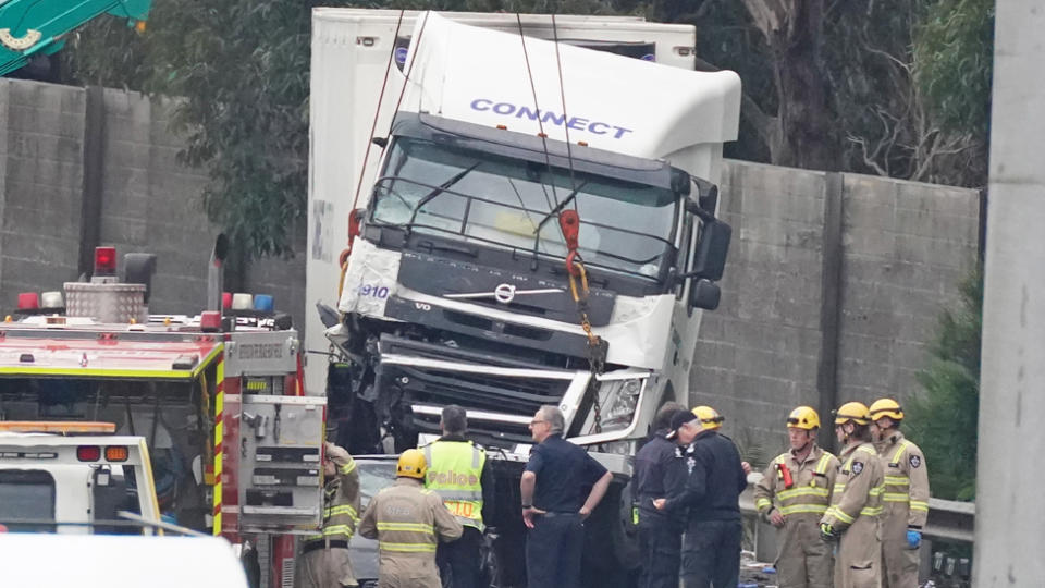 Police are seen standing in front of the crumpled truck and porsche.