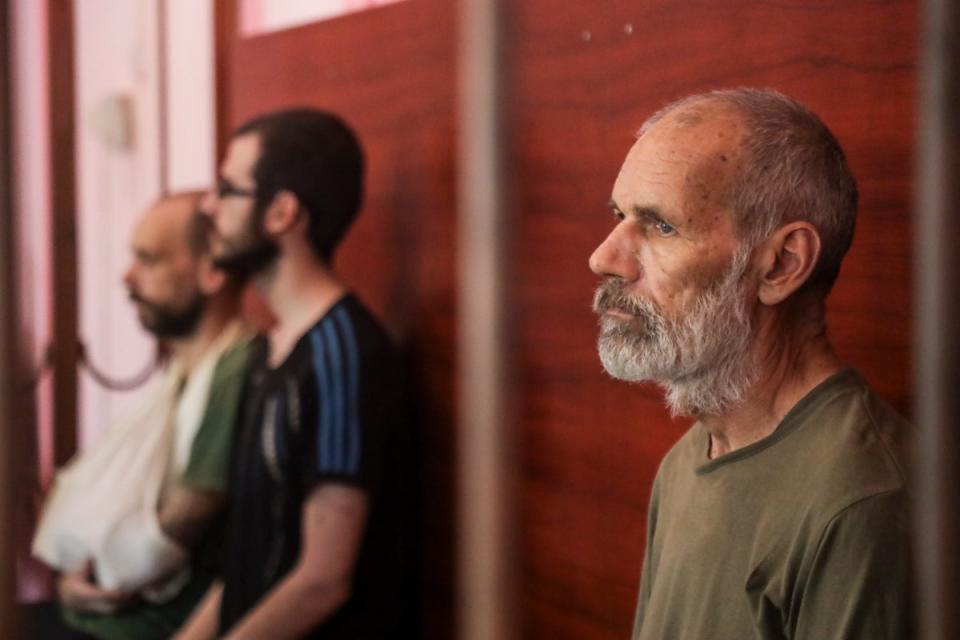 From left, the UK’s Andrew Hill, Dylan Healy and John Harding are seen behind bars (AP)