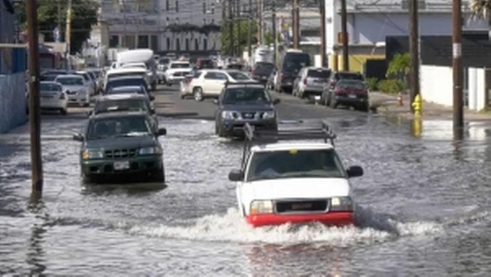 Vehicles drive through a flooded road in Honolulu.