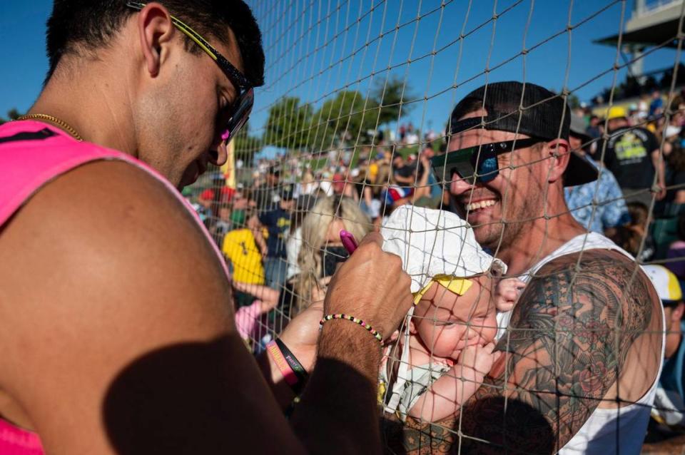 Austin Rioux, of Lincoln, holds a friend’s 3-month-old baby, Quinn, as Savanna Party Animals’ Jake Lialios (27) signs her hat before the Savannah Bananas World Tour on Saturday, July 29, 2023, at Sutter Health Park in West Sacramento.