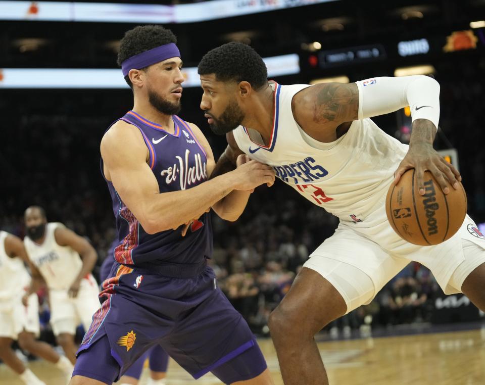 Phoenix Suns guard Devin Booker (1) defends against LA Clippers forward Paul George (13) during the first quarter at Footprint Center in Phoenix on Jan. 3, 2024.