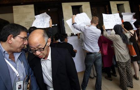 Delegates (L) take a detour as activists protest outside the plenary room of the ninth World Trade Organization (WTO) Ministerial Conference in Nusa Dua, on the Indonesian resort island of Bali December 6, 2013. REUTERS/Edgar Su