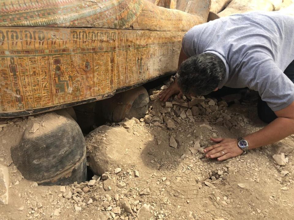 FILE - This Tuesday, Oct. 15, 2019 file photo provided by the Egyptian Ministry of Antiquities shows Egyptian Minister of Antiquities Khaled el-Anany looking at recently discovered ancient colored coffins with inscriptions and paintings, in the southern city of Luxor, Egypt. (Egyptian Ministry of Antiquities via AP, File)