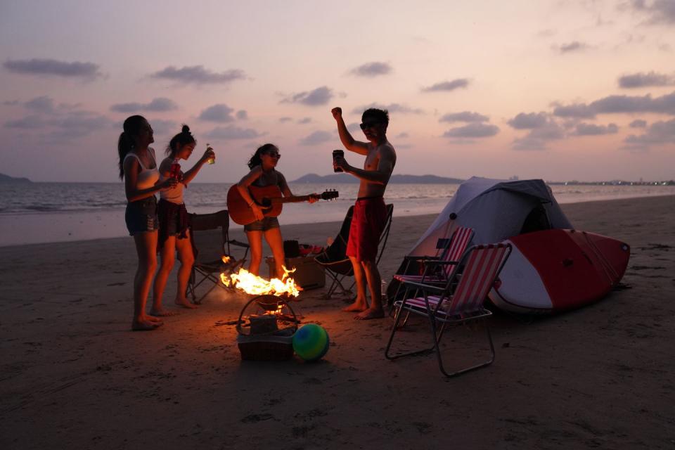 group friends are enjoy a bonfire on the beach