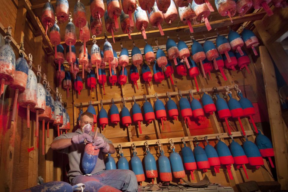 Lobsterman Kendall Delano sands last year's paint off lobster buoys he's painting in his workshop in Friendship, Maine, Thursday, May 10, 2012. Two lobster boats were recently sunk by vandals in Friendship, bringing back memories of territorial tensions in the industry that led to a shooting two summers ago. (AP Photo/Robert F. Bukaty)