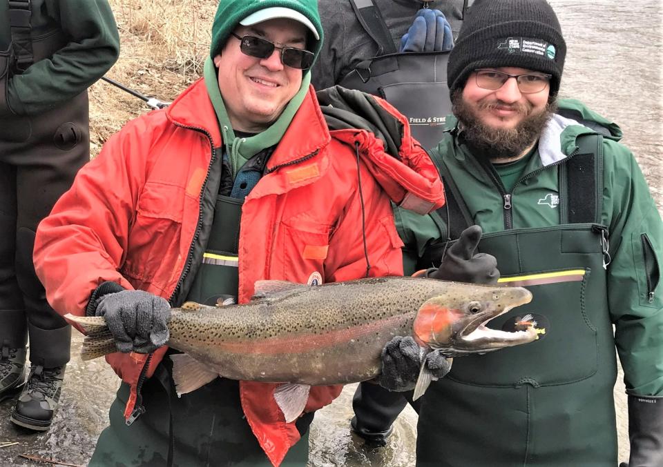 DEC regional fisheries biologist Brad Hammers, left, is all smiles as he displays a 10-pound male rainbow trout netted Tuesday, March 7, 2023 during a sampling of the annual spring trout spawning run up Catharine Creek.