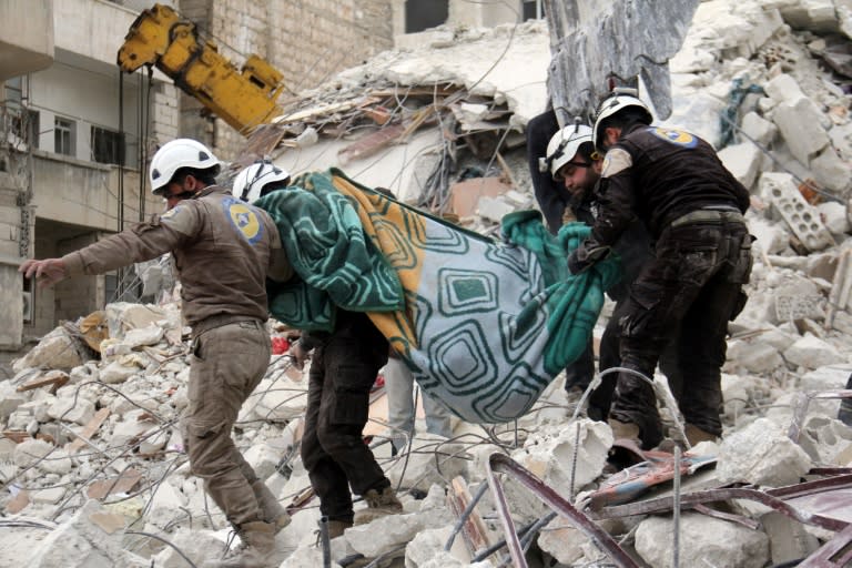 Syrian civil defence volunteers, known as the White Helmets, carry a body retrieved from the rubble following reported government air strike on the Syrian town of Ariha, in the northwestern province of Idlib, on February 27, 2017