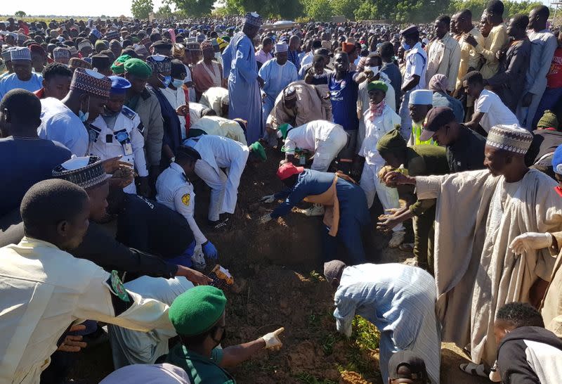 Men gather during the mass burial of people who were killed by militant attack, in Zabarmari
