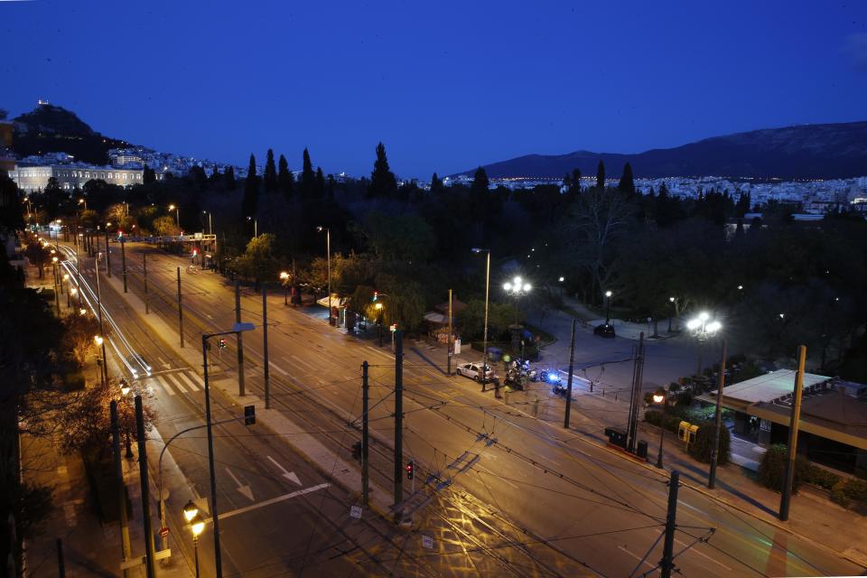 In this Thursday, April 2, 2020 photo, police gather at a checkpoint in the empty Amalias avenue, in central Athens during the lockdown. Deserted squares, padlocked parks, empty avenues where cars were once jammed bumper-to-bumper in heavy traffic. The Greek capital, like so many cities across the world, has seen its streets empty as part of a lockdown designed to stem the spread of the new coronavirus. (AP Photo/Thanassis Stavrakis)