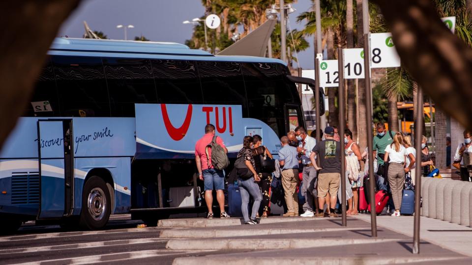 Touristen mit Mundschutz holen ihr Gepäck aus einem Bus des Tourismuskonzerns Tui nahe des Flughafens auf Tenerife.