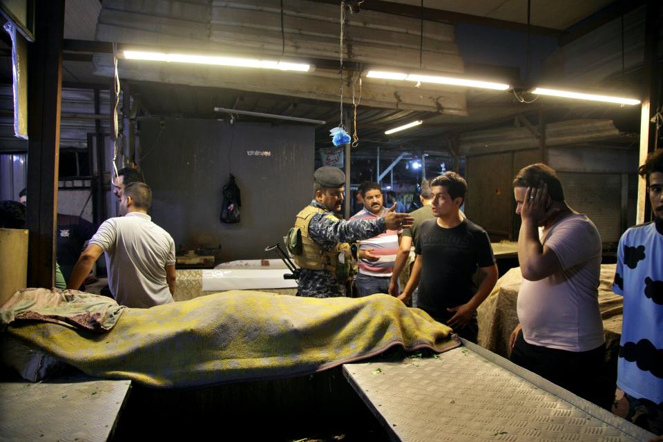 People and security forces gather at the site of a bombing in Wahailat market in Sadr City, Iraq, Monday, July. 19, 2021. A roadside bomb attack targeted the Baghdad suburb Monday, killing several and wounding dozens of others at a crowded market, Iraqi security officials said. (AP Photo/Khalid Mohammed)