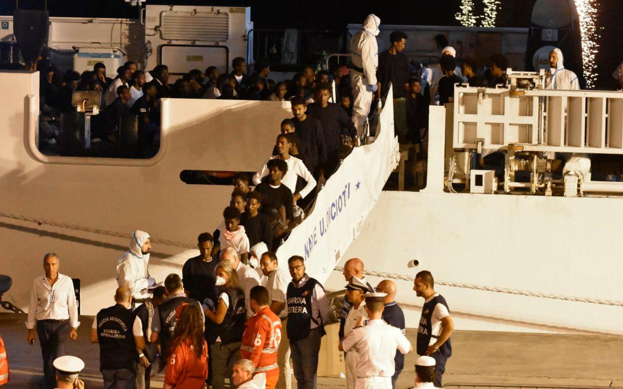 Migrants disembark from the Italian Coast Guard ship