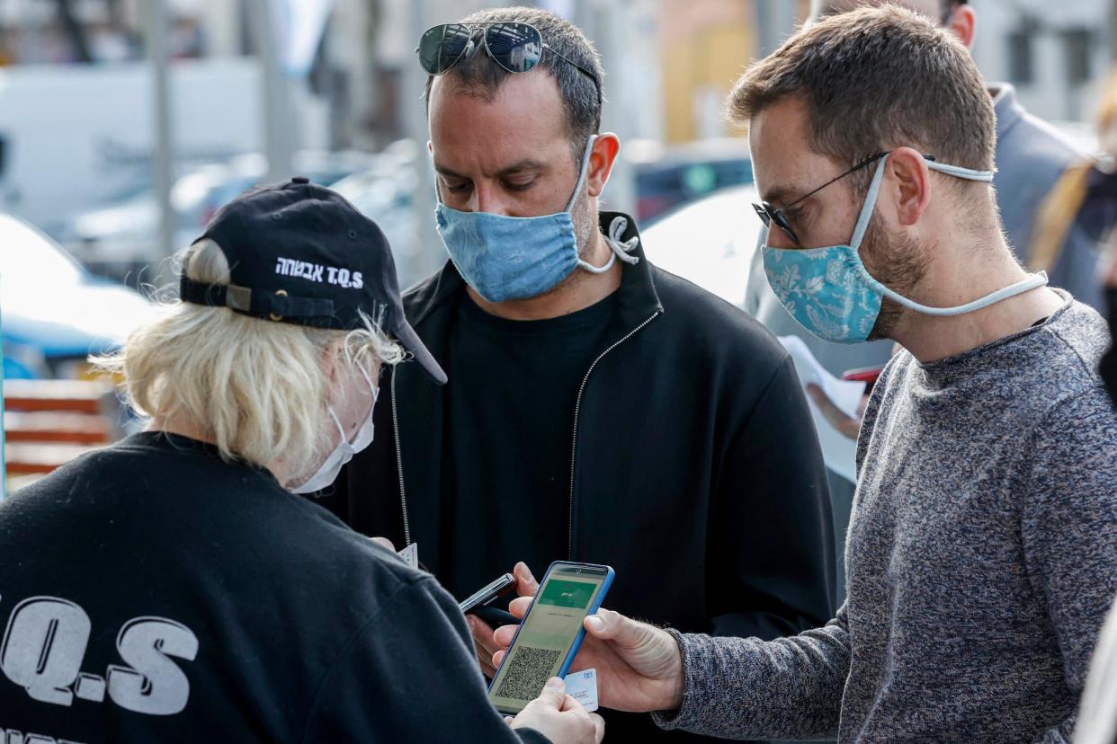 Des Israéliens montrant leur certificat de vaccination, à l'entrée d'un stade de Tel Aviv, le 5 mars 2021 - JACK GUEZ / AFP