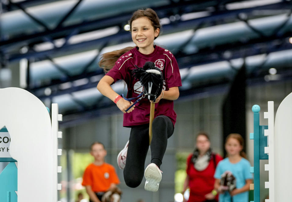 A participant clears the bar during the first German Hobby Horsing Championship in Frankfurt, Germany, Saturday, Sept. 14, 2024. (AP Photo/Michael Probst)