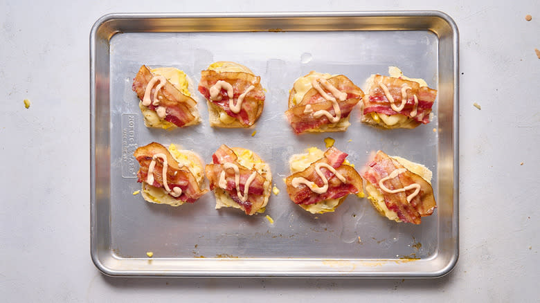 egg and bacon breakfast sandwiches in assembly on sheet tray